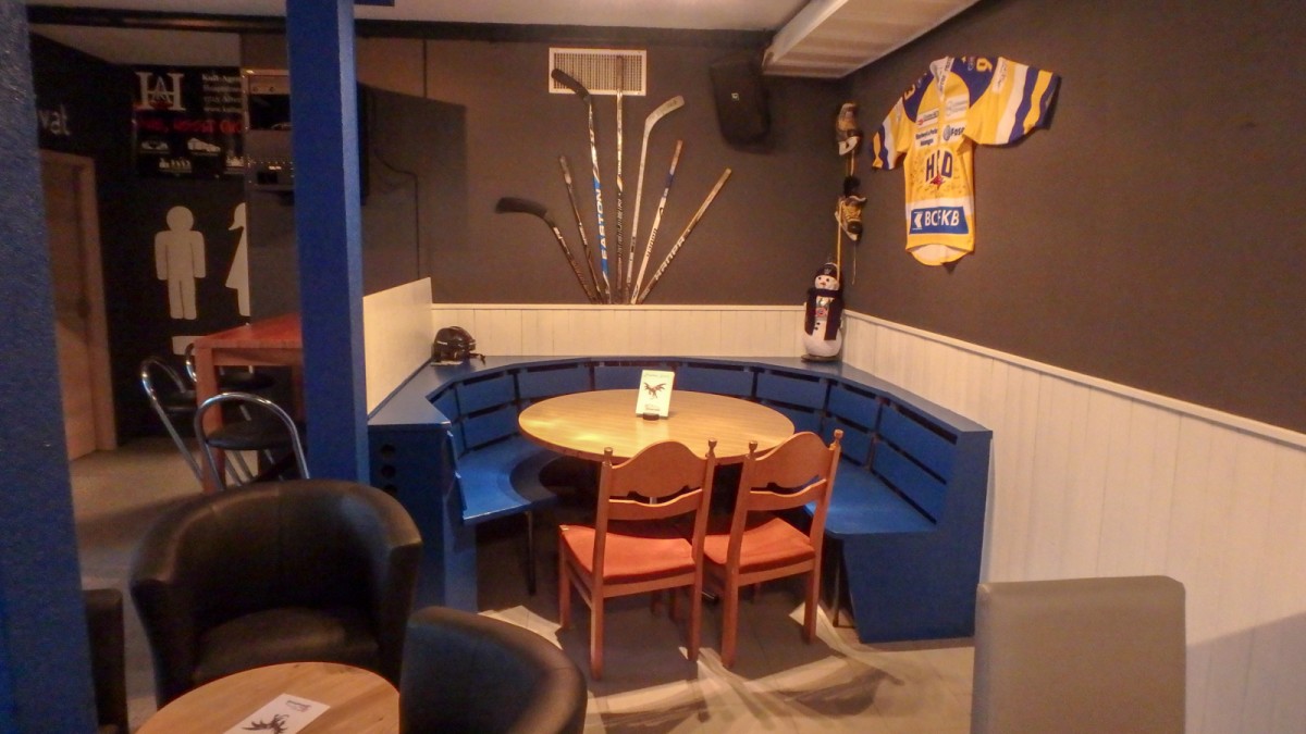 Eishockey-Stube mit Trikot und Stöcken an der Wand